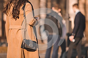 rear view of woman in brown topcoat walking by street