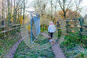 Rear view of a woman entering with her dachshund into Dutch natural ecological reserve