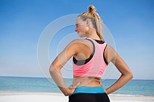 Rear view of woman with hand on hip at beach