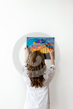 Rear view of woman hanging picture on the wall