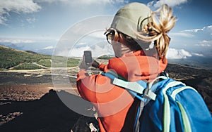 Rear view of woman hiker taking photo with smart phone