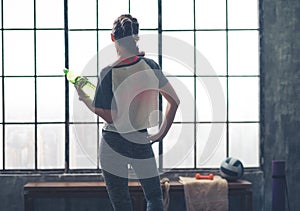 Rear view of woman looking out of loft gym holding water bottle