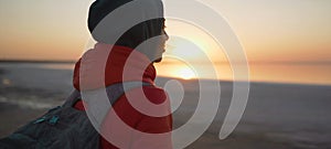 Rear view woman looking at sunrise at sea beach in front golden sunlight, enjoying landscape