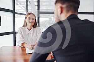 Rear view. Woman and man in formal clothes working together indoors in the office by table