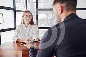 Rear view. Woman and man in formal clothes working together indoors in the office by table