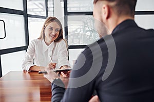 Rear view. Woman and man in formal clothes working together indoors in the office by table