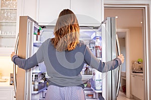 Rear view of woman opening the fridge at home