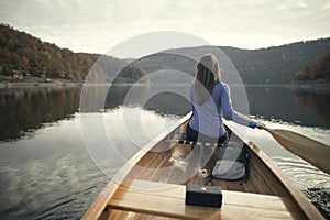 Rear view of woman paddling canoe on lake