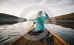 Rear view of woman paddling canoe on lake