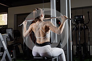 Woman doing lat pulldown on cable machine in gym, back workout concept