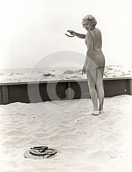 Rear view of woman playing horseshoes at the beach