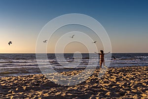 Rear view of a woman in the red swimsuit running on the beach on the Atlantic Ocean in Portugal