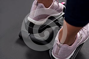 Rear view of woman`s foots wearing sports shoes using stepper