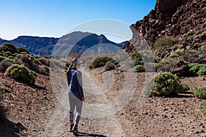 Rear view of woman on scenic hiking trail through a canyon near Montana Majua in volcano Mount Teide National Park, Tenerife photo