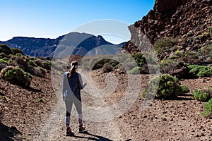 Rear view of woman on scenic hiking trail through a canyon near Montana Majua in volcano Mount Teide National Park, Tenerife photo