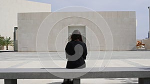 Rear view of woman sitting on bench at footpath