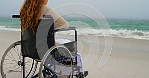 Rear view of woman sitting on wheelchair at beach 4k