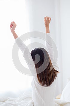 Rear view of woman stretching in bed after wake up in morning.