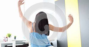 Rear view of woman stretching and waking up in bedroom