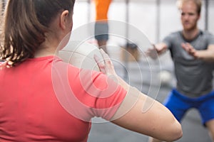 Rear view of woman throwing medicine ball towards man in crossfit gym