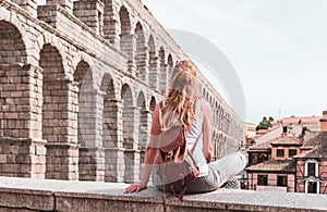 rear view of woman tourist enjoying view of Roman aqueduct on plaza del Azoguejo in Spain