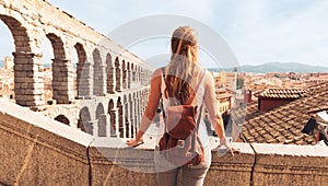 rear view of woman tourist enjoying view of Roman aqueduct on plaza del Azoguejo in Spain