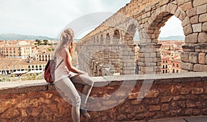 rear view of woman tourist enjoying view of Roman aqueduct on plaza del Azoguejo in Spain