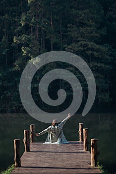 Rear view of a woman tourist sitting at the wooden walkway through the lake at Pang Oung, Mae Hong Son, Thailand