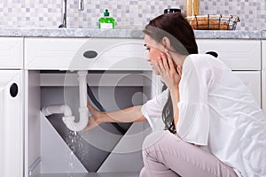 Woman Trying To Stop Water Leakage From Sink Pipe photo