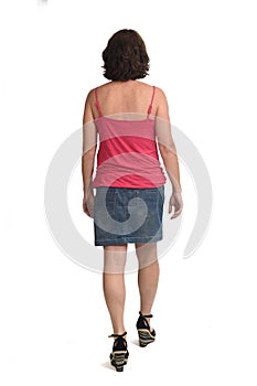 Rear view of a woman walking with denim skirt on white background