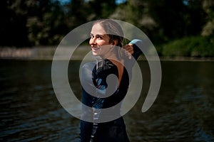 Rear view of woman in wetsuit with open zipper and her head turned