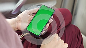 rear view of women sitting on car holding smart phone with green screen
