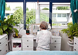 Rear view of woman sitting at dresser in bedroom