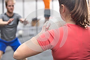 Rear view of woman throwing medicine ball towards man in crossfit gym