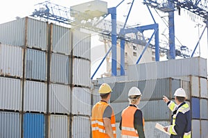 Rear view of workers inspecting cargo containers in shipping yard