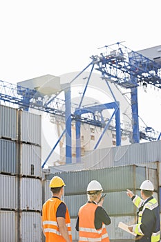 Rear view of workers inspecting cargo containers in shipping yard