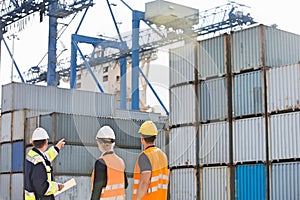 Rear view of workers inspecting cargo containers in shipping yard