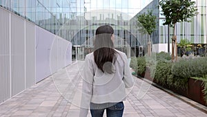 Rear view of young adult business woman walking in a co-working office area.