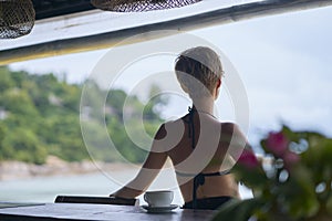 Rear view of young Asian beauty sitting, relaxing at beach bar in vacation