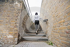 Rear view of young asian businesswoman walking up stairs