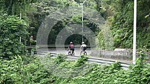 rear view of young asian cyclists riding around a curve