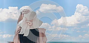 Rear view young Asian woman standing of happy attractive with hands holding sun hat up, sunny day, summer sea, blue sky background