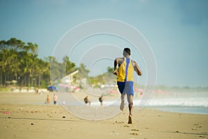 Rear view of young athletic and fit african american sport man doing running workout on sunset at the beach training hard jogging