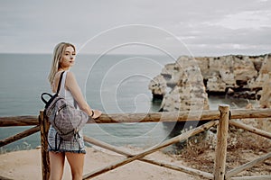 Rear view of Young beautiful woman traveler looking at sunset and beautiful seascape with a lookout point. Freedom, travel, vacati