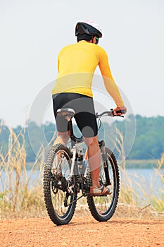 rear view of young bicycle man wearing rider suit and safety helmet riding mountain bike on dirt ground use for man and male act