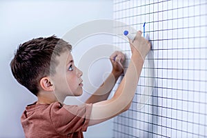 Rear view of young boy solving math problems on white board