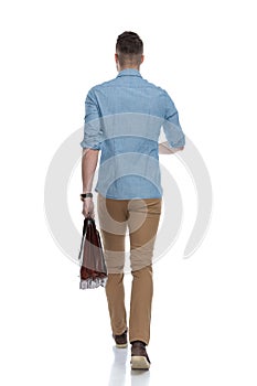 Rear view of young casual holding briefcase, walking