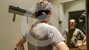Rear view of a young Caucasian handsome man trying new clothes i