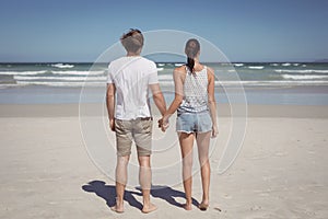 Rear view of young couple holding hands at beach