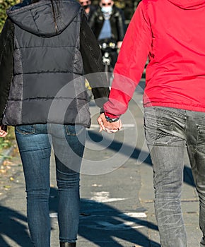 Rear view of a young couple holding hands on the street